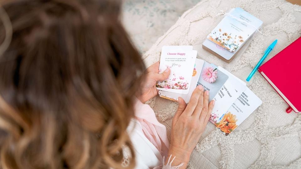 Woman fanning out affirmation cards on a decorative pillow