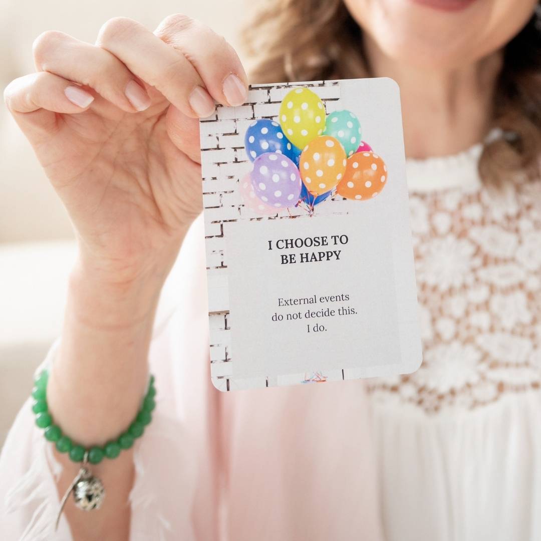 Woman holding affirmation card close to camera that says I choose to be happy