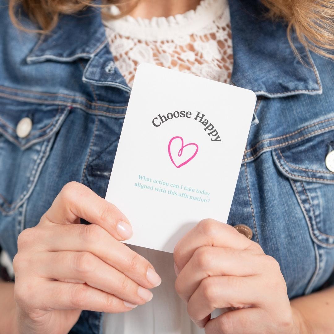 Marie close up on jean jacket holding one card with the words Choose Happy and a pink heart